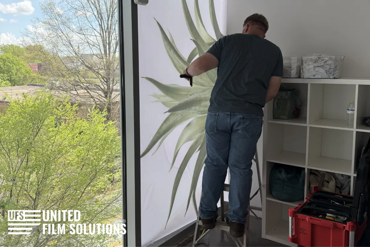 Installer applying decorative vinyl and decals to a commercial window.
