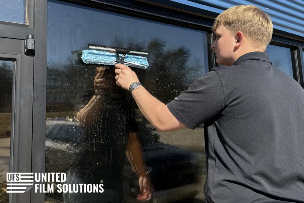 Technician washing a commercial window with a squeegee.